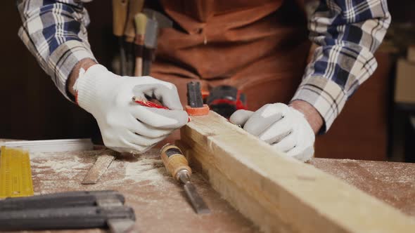 Working Carpenter is Drawing on a Piece of Wood