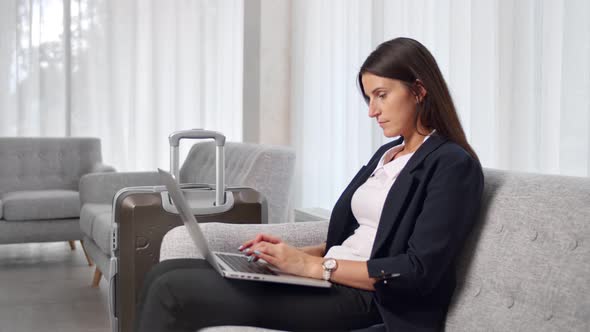 Busy Young Businesswoman Working Using Laptop Sitting on Couch During Business Trip