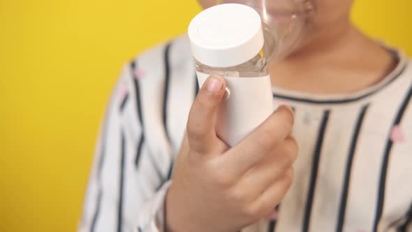 Child Girl Hand Hold a Nebulizer Against Yellow Background