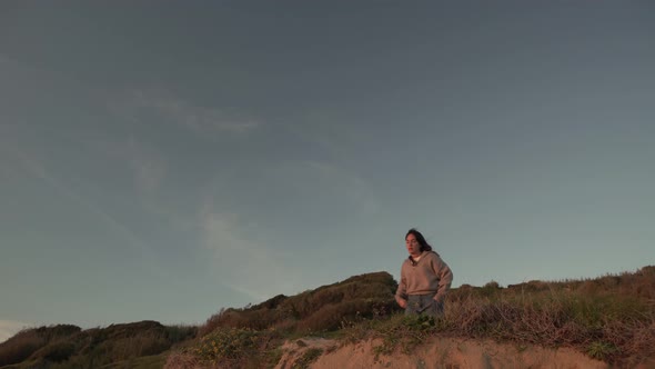 Traveling woman standing on hill at sunset