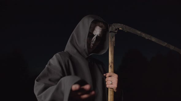 Grim Reaper with Scythe Gesturing To Follow at Dusk