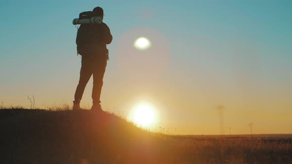 Silhouette of a Man with a Backpack Against Bright Sky Sunset