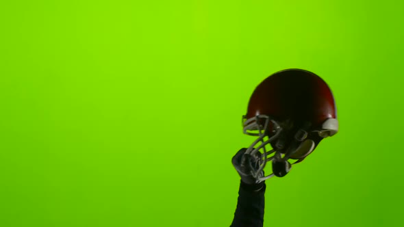 Football Player's Hand Raises a Red Protective Helmet. Green Screen
