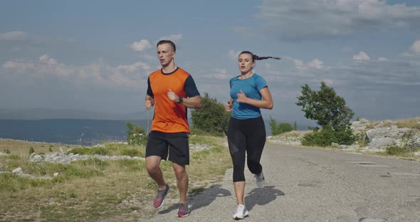 Tracking Slow Motion Shot of Sportive Couple Jogging Outdoors in the Morning Trail Running