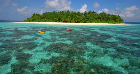 Aerial drone view of a man and woman couple kayaking around a tropical island