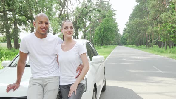Young Happy Couple Relaxing Near Their Car Admiring Nature of Countryside