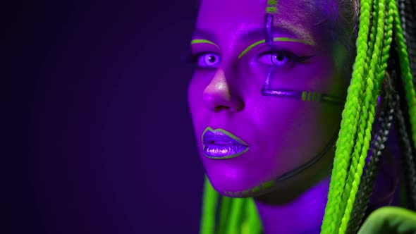 Headshot of Slim Woman with Futuristic Makeup Looking at Camera As Strobe Lights Turning on