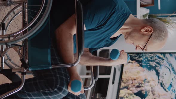 Vertical Video Man with Disability Using Dumbbells to Stretch Arms Muscles