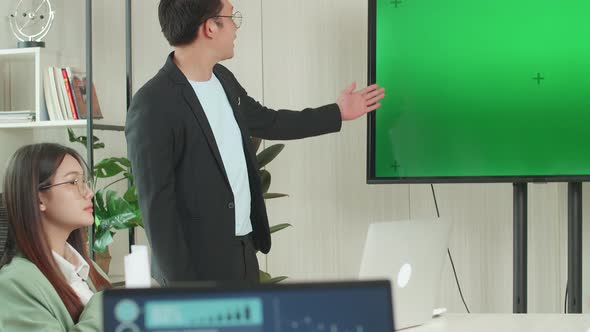 Asian Businessman Presentation To His Business Colleagues, Pointing At Tv Mock Up Green Screen