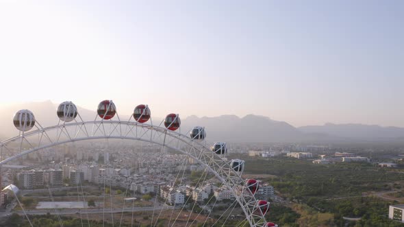 Ferris Wheel in Amusement Park on the Background of Urban Landscape