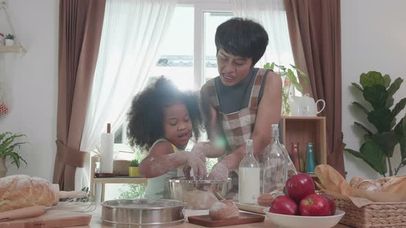 African American parents with girls enjoying music dancing and cooking food. Family in kitchen