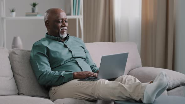 African Bald Overweight Obese Old Middleaged Man Senior Businessman Sitting on Sofa at Home Working