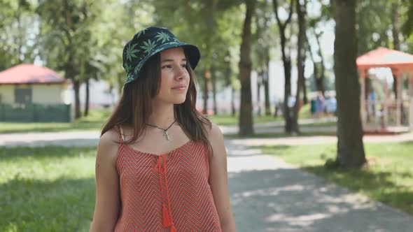 A Teenage Girl in a Panama Hat is Walking Through the Park in the Summer