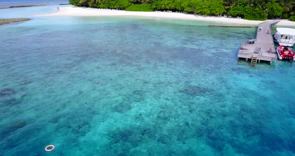 Natural flying tourism shot of a sandy white paradise beach and aqua blue water background in colorf