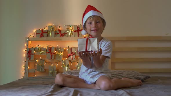 a Little Boy Opening a Present From an Advent Calendar Which Is Hanging on a Bed That Is Lightened