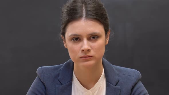 Strict Female Teacher Looking at Camera Against Blackboard Background, Class