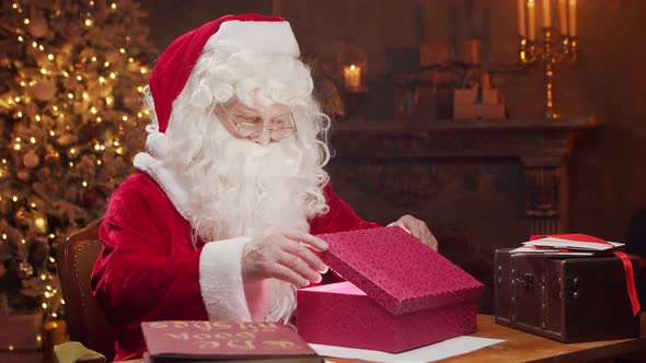 Workplace of Santa Claus. Cheerful Santa is working while sitting at the table.