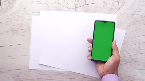 Top View of Man Hand Using Smart Phone and Empty Paper on Table