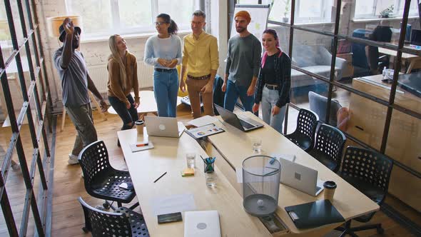 Millennial Colleagues Having Fun in Office Playing Basketball Game Throwing Paper in Rubbish Bin