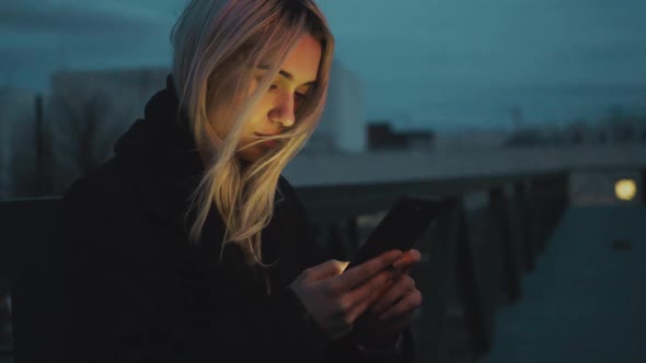 Young woman standing near road with smartphone