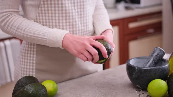 Close Up of Woman Hands Halving Avocado at the Domestic Kitchen