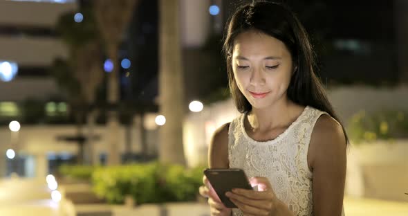 Woman using smart phone in city at night 