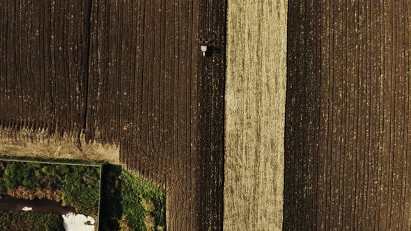 Wide Aerial top view shot of Agricultural machine driving in brown fields