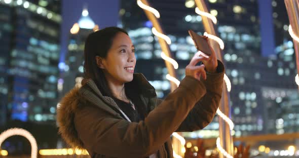 Woman using mobile phone for taking photo in the beautiful city background at night