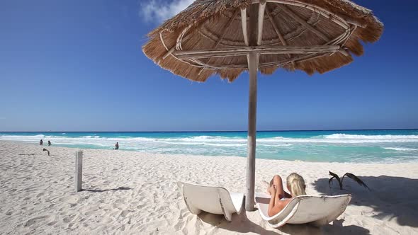 Woman Relaxing on Caribbean Beach with Sun Umbrellas and Beds