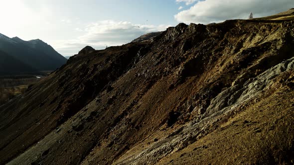 Hilly Mountains Against a Background of Blue Sky and Gray Clouds Illuminated By the Sun