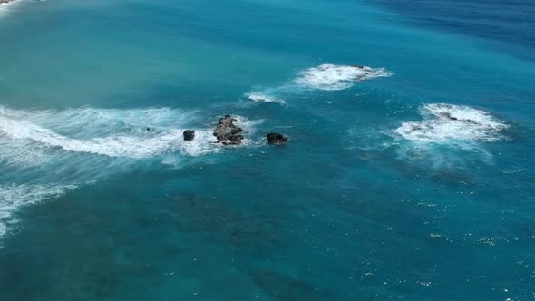 Beautiful aerial view of the many shades of clear blue water of the Caribbean as waves break over la