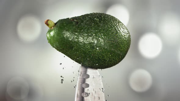 Fresh Avocado Falling Down with Drop on Knife Stuck