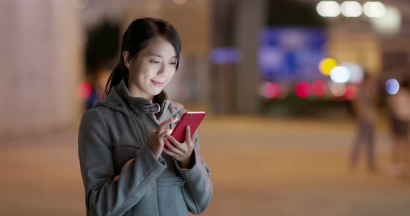 Woman check on smart phone in city at night