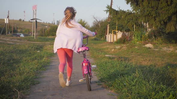 Girl Teen Riding Bike in Summer in City at Sunset.