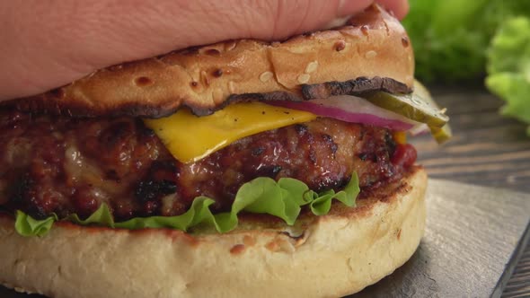 Close-up of the Hand Pressing a Sesame Bun To the Fresh Homemade Grilled Burger