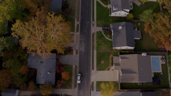 Overhead flyover of a suburban street and houses in Autumn.