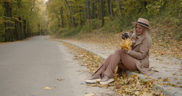 Woman Sitting on the Side of the Alley with a Pet in Her Arms