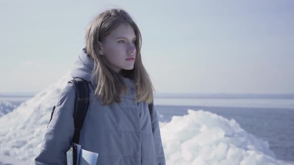 Portrait of Young Blond Pretty Woman in Warm Jacket Standing on the Glacier with the Map in Hands