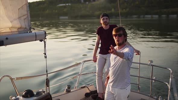 Two Friends Who Are Engaged in Sailing Enjoy the Sunset in the Evening