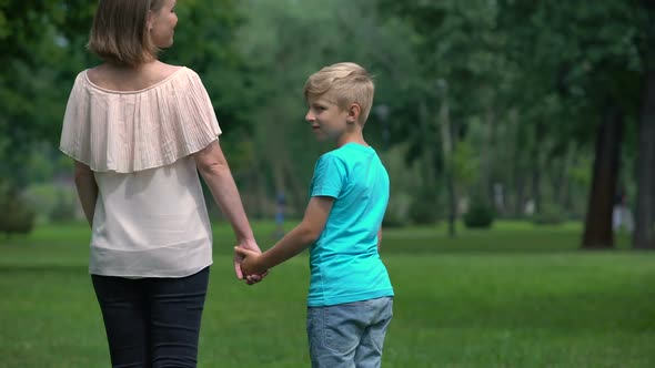 Woman and Boy Holding Hands, Walking Away Together, Social Protection Concept