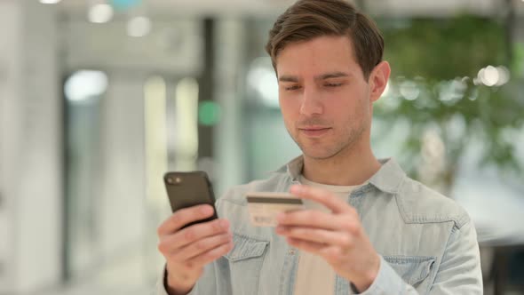 Portrait of Creative Young Man Making Successful Online Payment on Smartphone