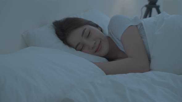 Asian beautiful comfort girl in pajamas lying down on bed sleep in dark night in bedroom at home.