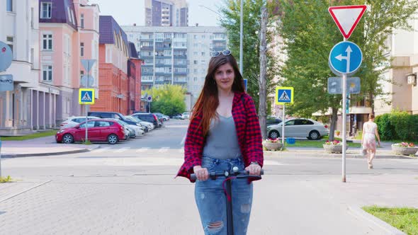 A Smiling Woman is Riding an Electric Scooter in the Street