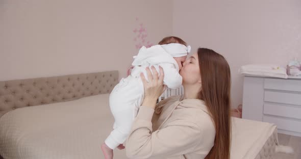 Happy Young Mother Tenderly Caresses Her Newborn Baby Holding Her In Her Arms