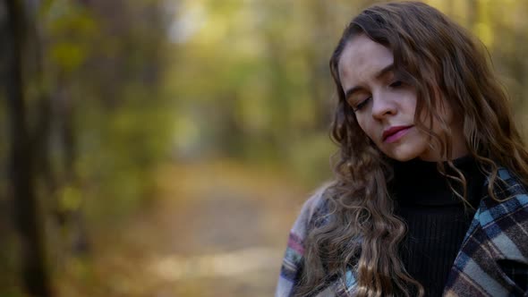 Sad and Melancholic Woman is Walking Alone in Forest in Autumn Feeling Headache