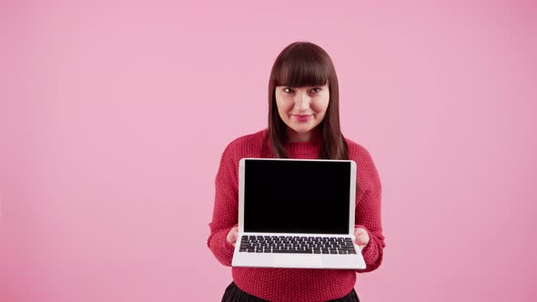 White Woman with Dark Long Hair and Fringe Wearing Red Sweater and Holding Laptop Computer with