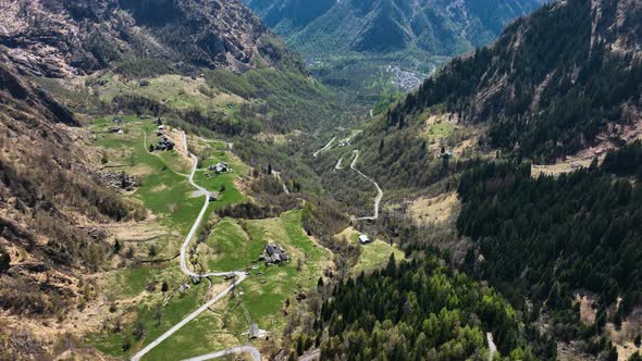 Twisted road through small secluded village in Italian alp valley - drone