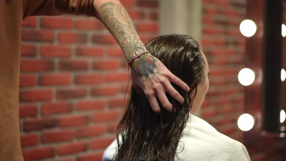 Unrecognizable Hairstylist Stroking Long Shiny Brunette Hair in Beauty Salon Indoors