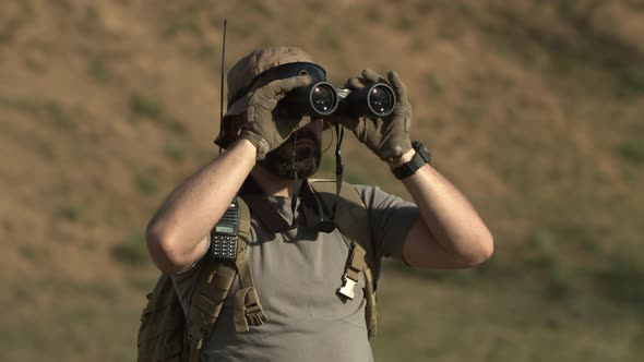 Outdoor Shot of Serious Soldier or Hunter in Military Tshirt Hat with Sunglasses Holding Backpack