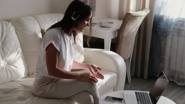 Young Woman Wears Headset Talking on Laptop with Online Teacher Studying While Working From Home